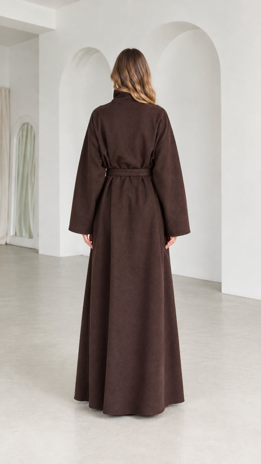 Back view of model wearing full length brown high neck coat with belt