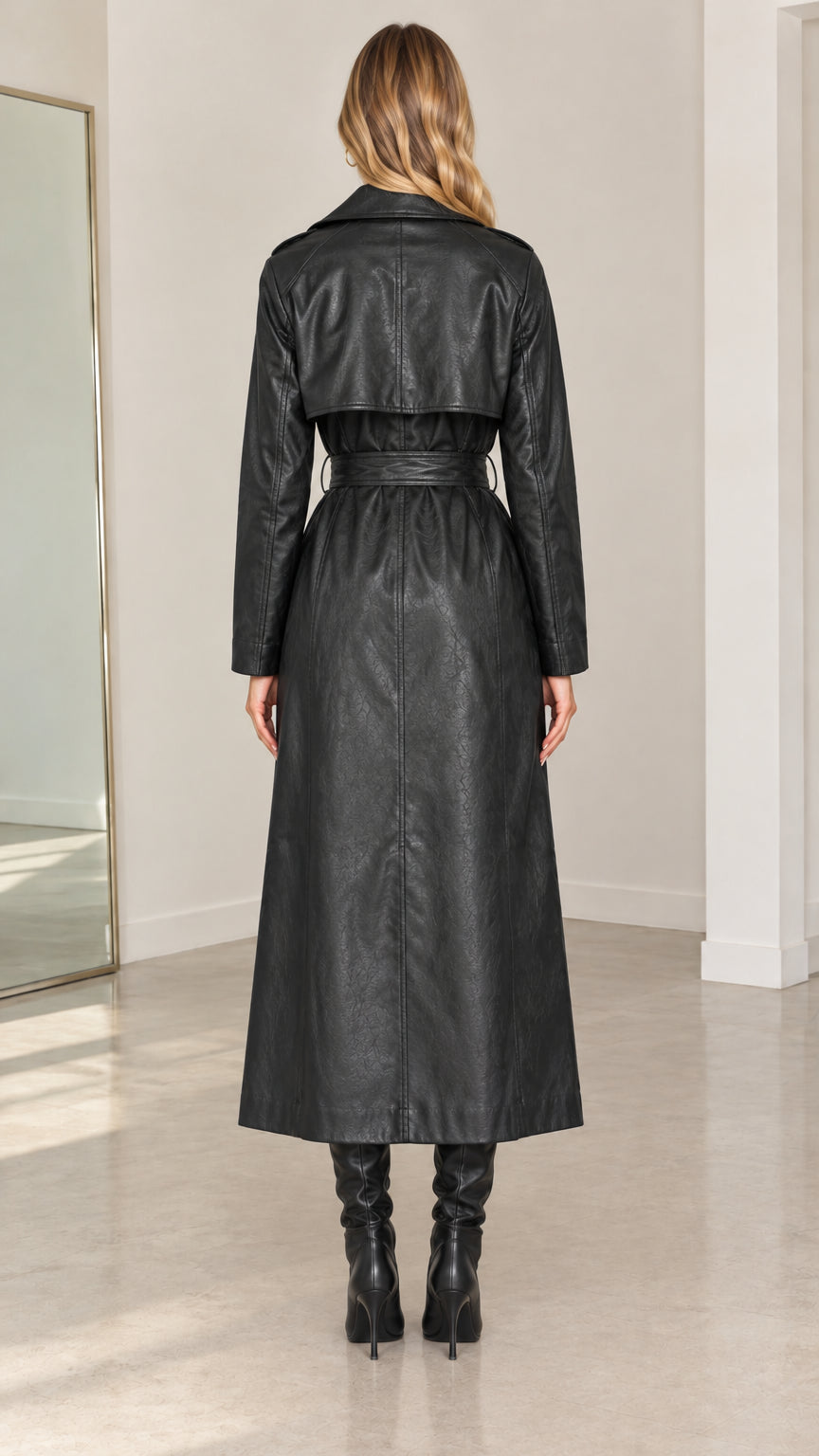 Back view of model wearing black maxi faux leather trench coat showing rear storm flap