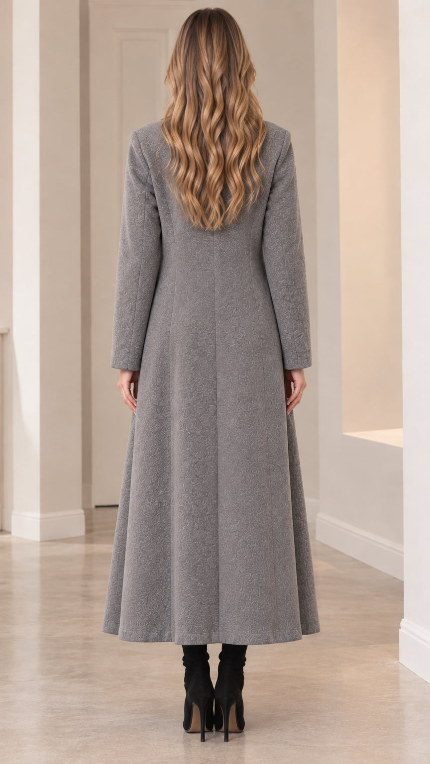 Back view of model in grey maxi overcoat highlighting clean back tailoring