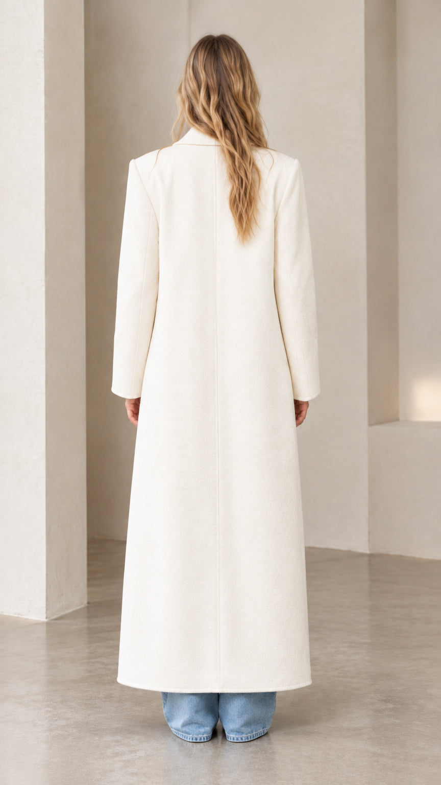 Back view of the cream longline maxi overcoat showing clean tailoring and structured drape