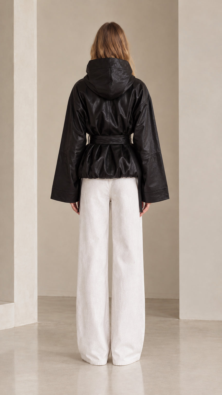 Back view of black hooded faux leather jacket highlighting hood and gathered cinched waist