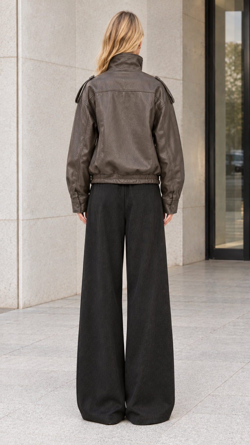 Back full-body view of model showing charcoal brown faux leather bomber jacket silhouette and elastic waist