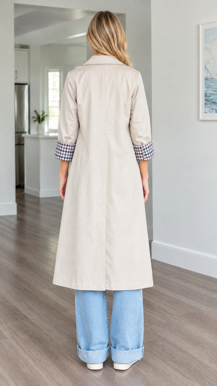 Back view of woman wearing beige midi trench coat showing back vent and check cuffs