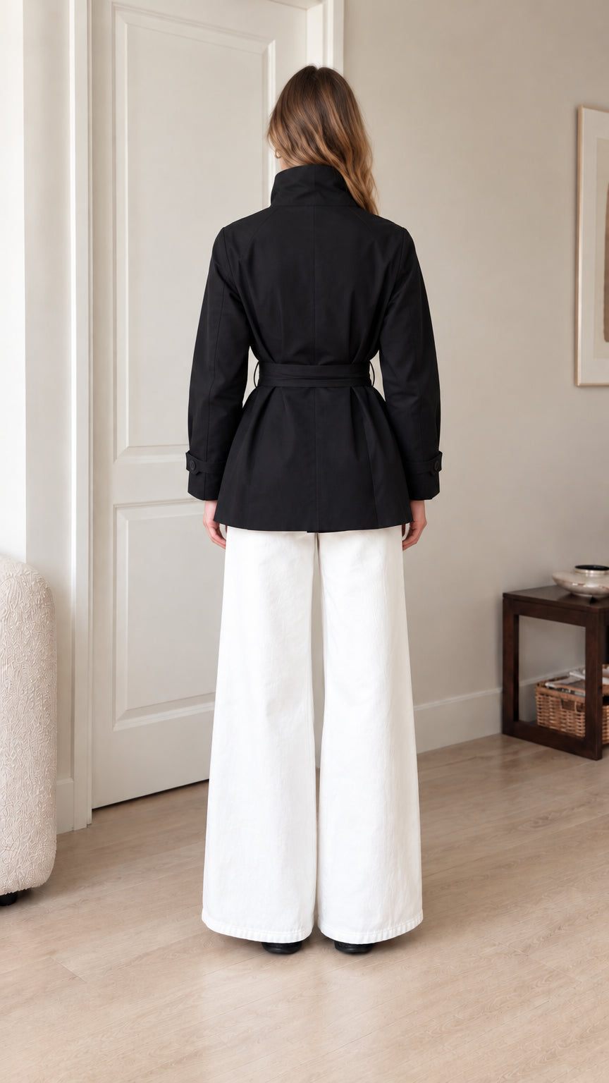 Back view of model wearing black tie-waist short trench jacket