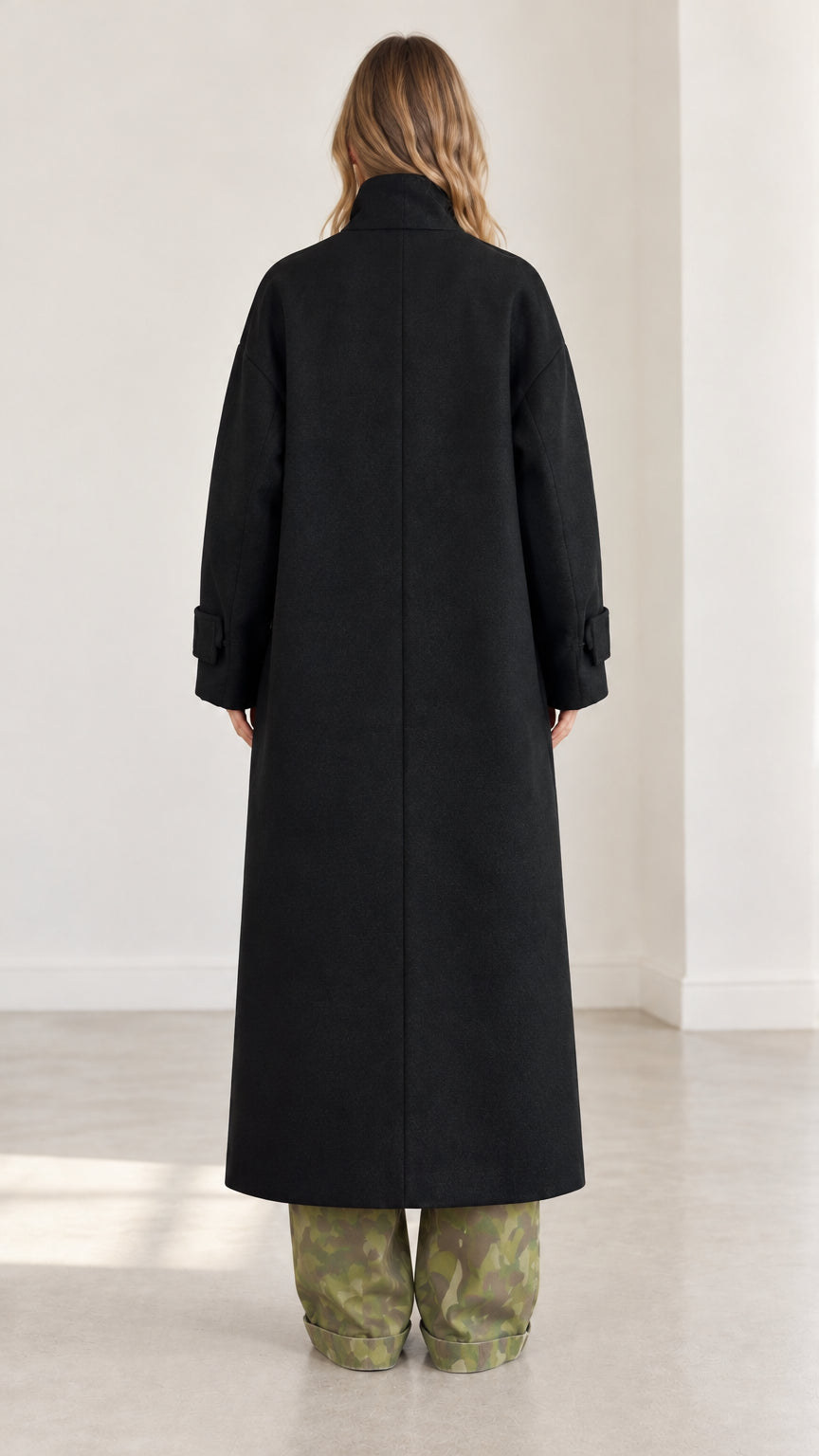 Rear back view of full-length black tailored overcoat showing straight hemline