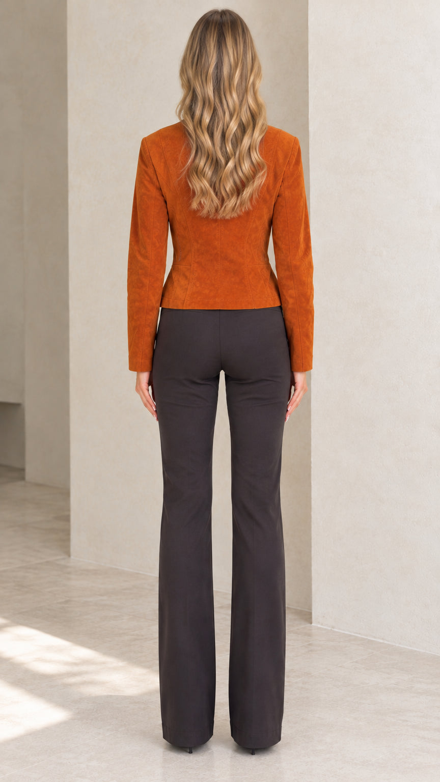 Back view of model showcasing tailored fit of cognac faux suede jacket and flare trousers