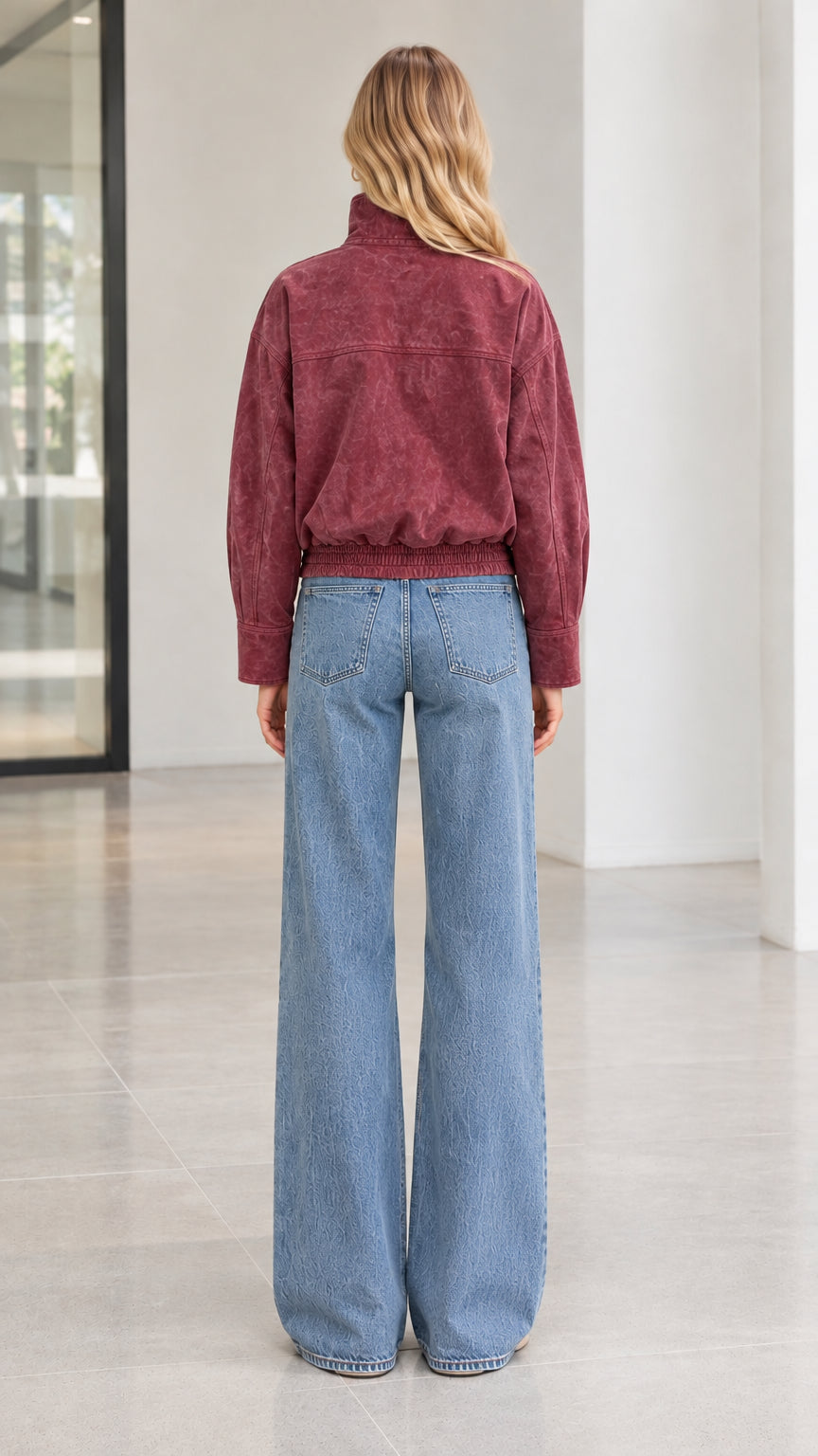 Back view of woman wearing burgundy corduroy bomber jacket with elastic hem