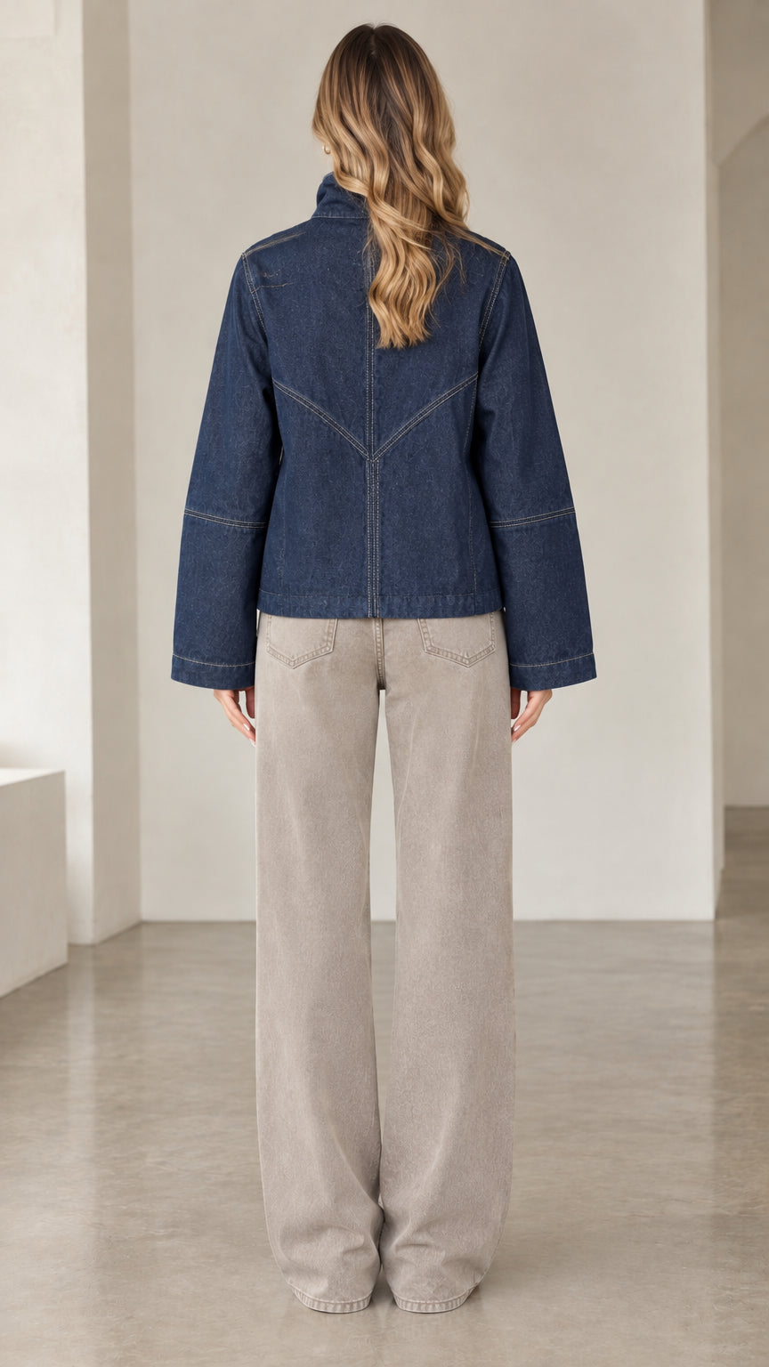 Back view of model showing geometric topstitch seam detailing on dark blue denim jacket