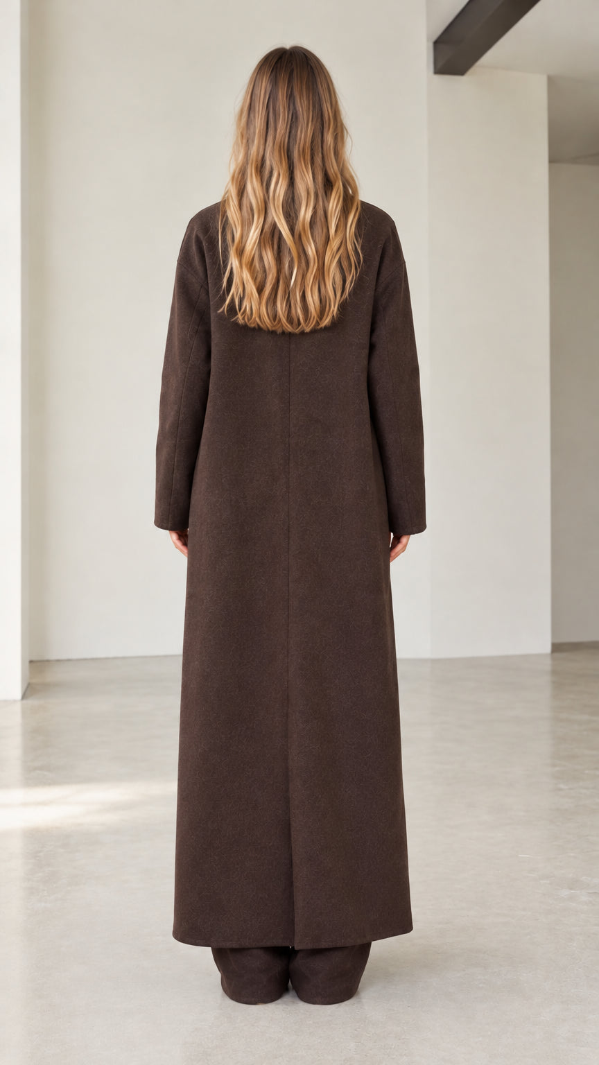 Back view of woman wearing long dark brown coat showing clean tailored line
