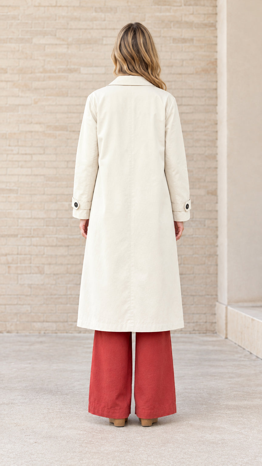 Back full-length view of woman in cream single-breasted longline coat