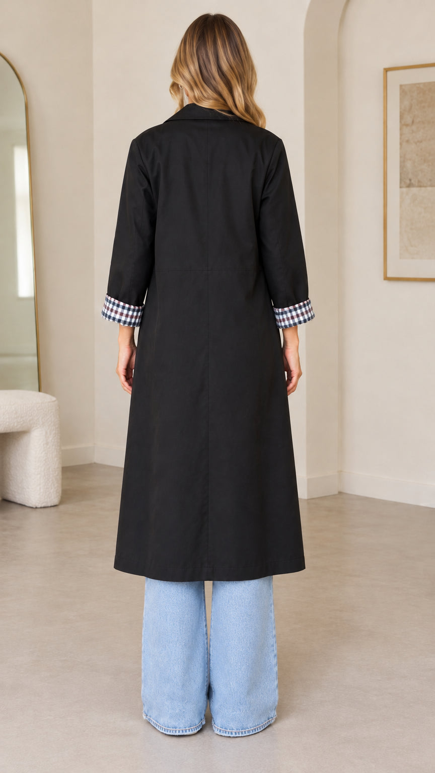 Back full-length view of woman wearing black long trench coat