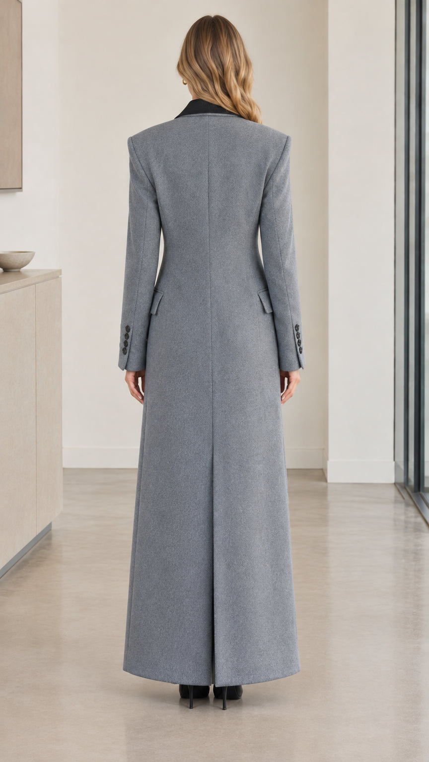 Back full-length view of woman wearing grey long overcoat showing center slit