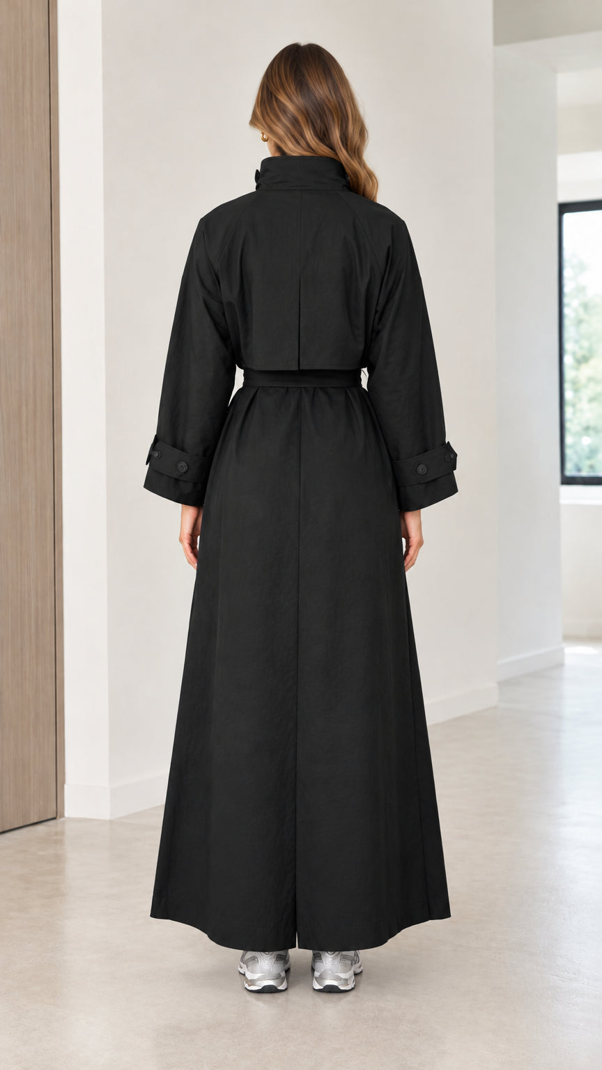 Back view of a woman wearing a long black belted trench coat