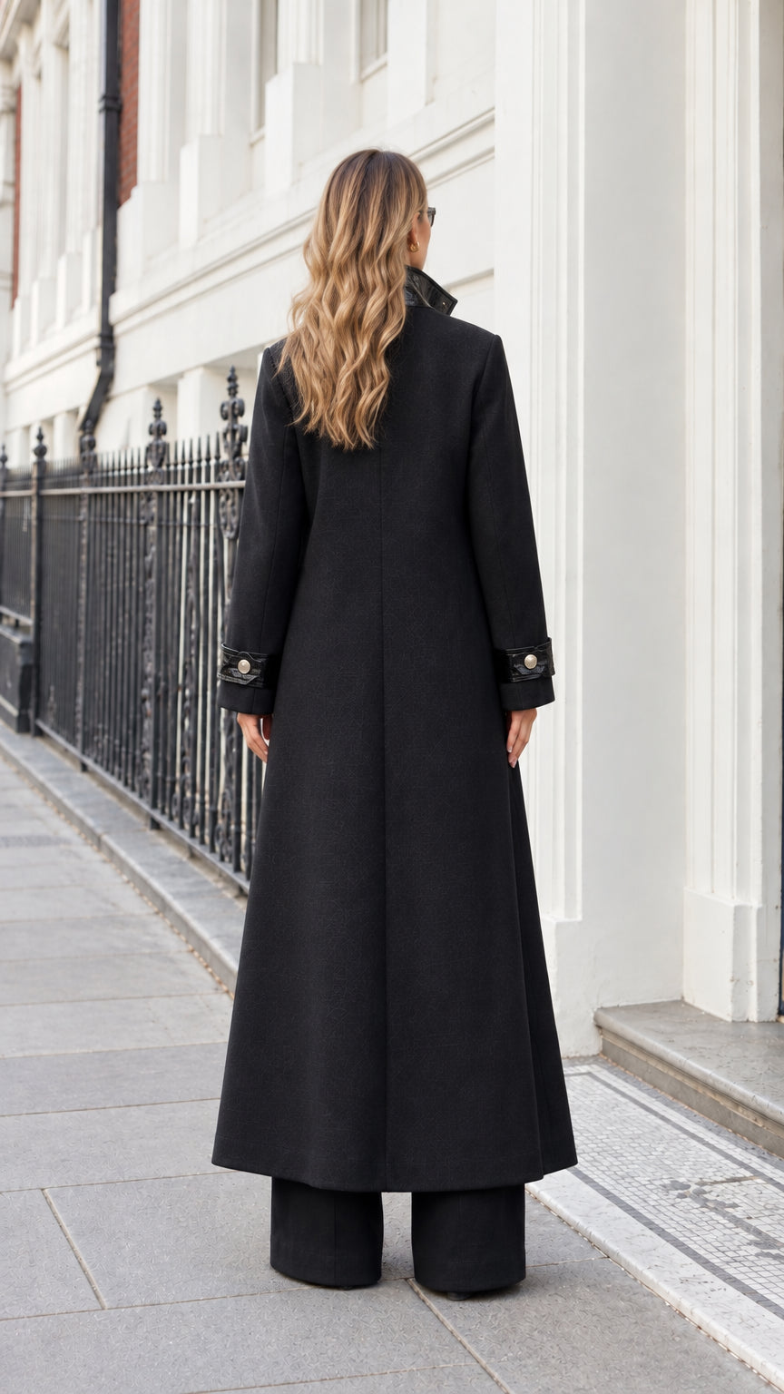 Back full-length view of woman wearing black maxi tailored overcoat highlighting sleek clean drape