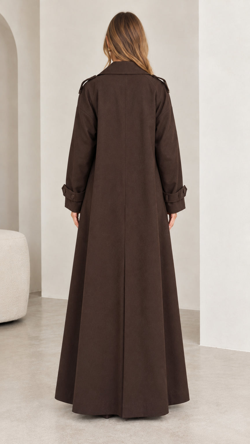 Back view of model showing the full length and back vent pleat of the brown trench coat