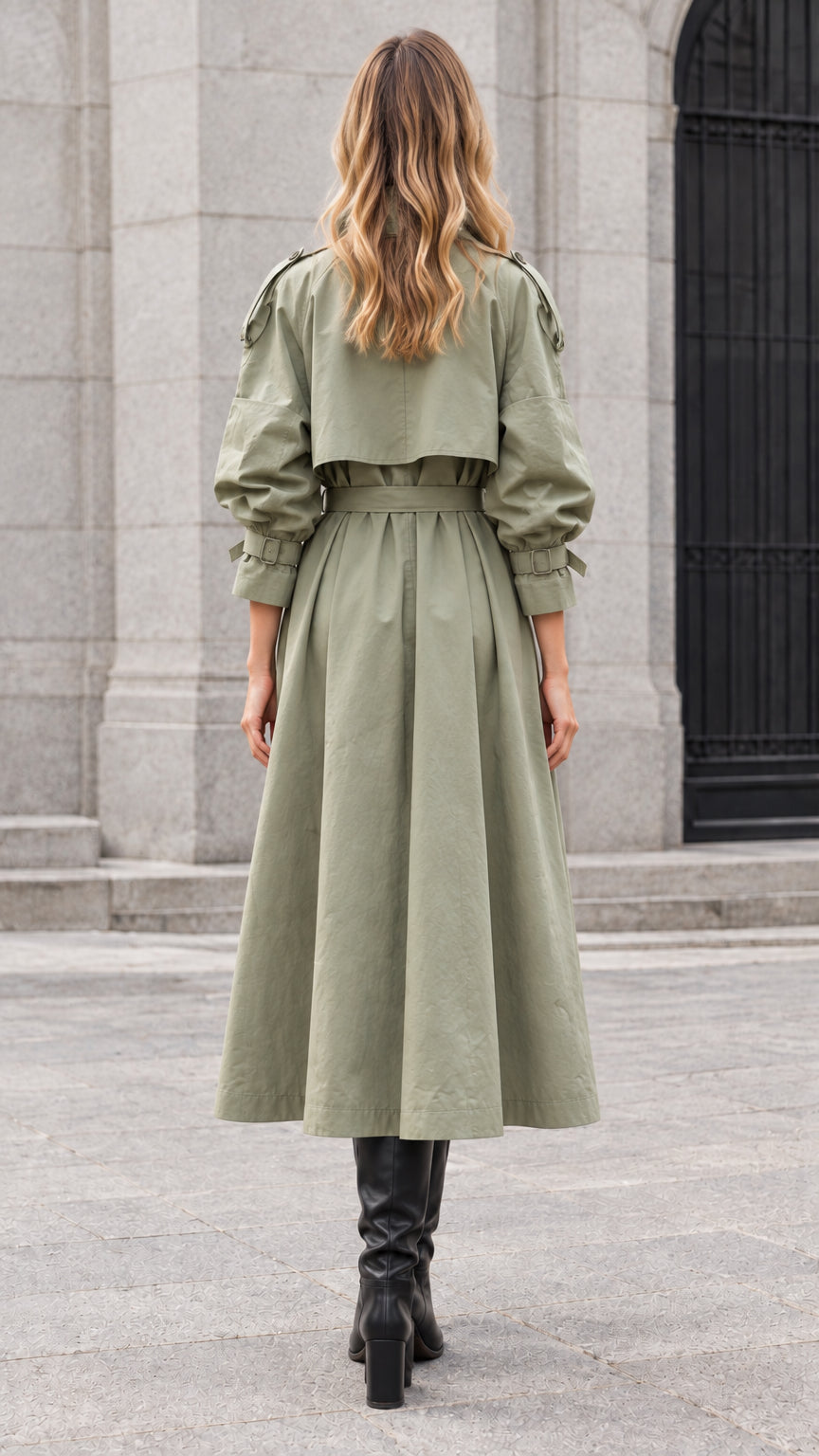 Back view of model wearing sage green long belted trench coat with back storm flap