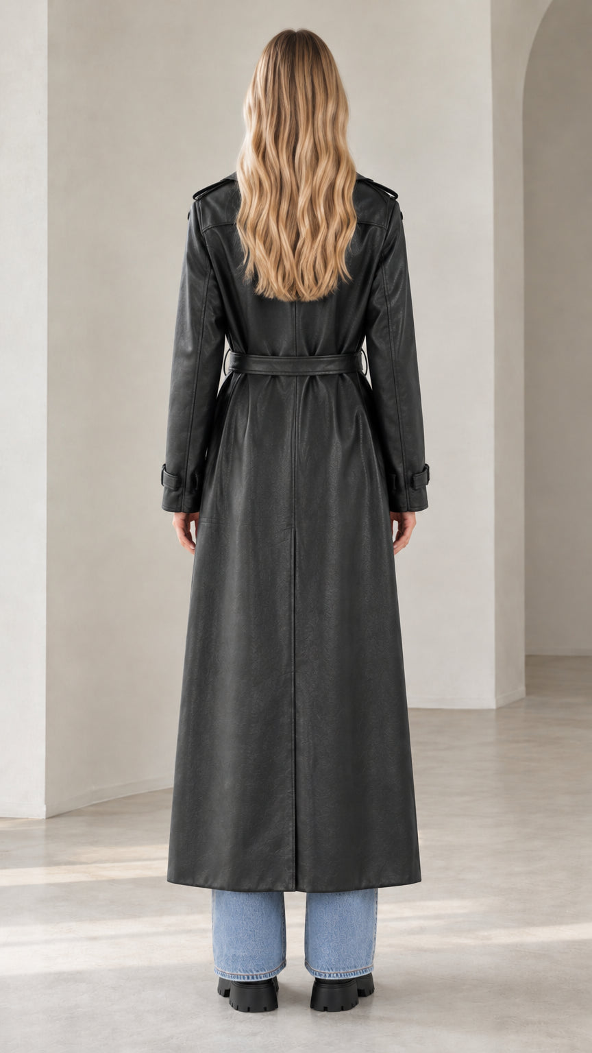 Back view of model wearing belted black faux leather maxi trench coat with center vent