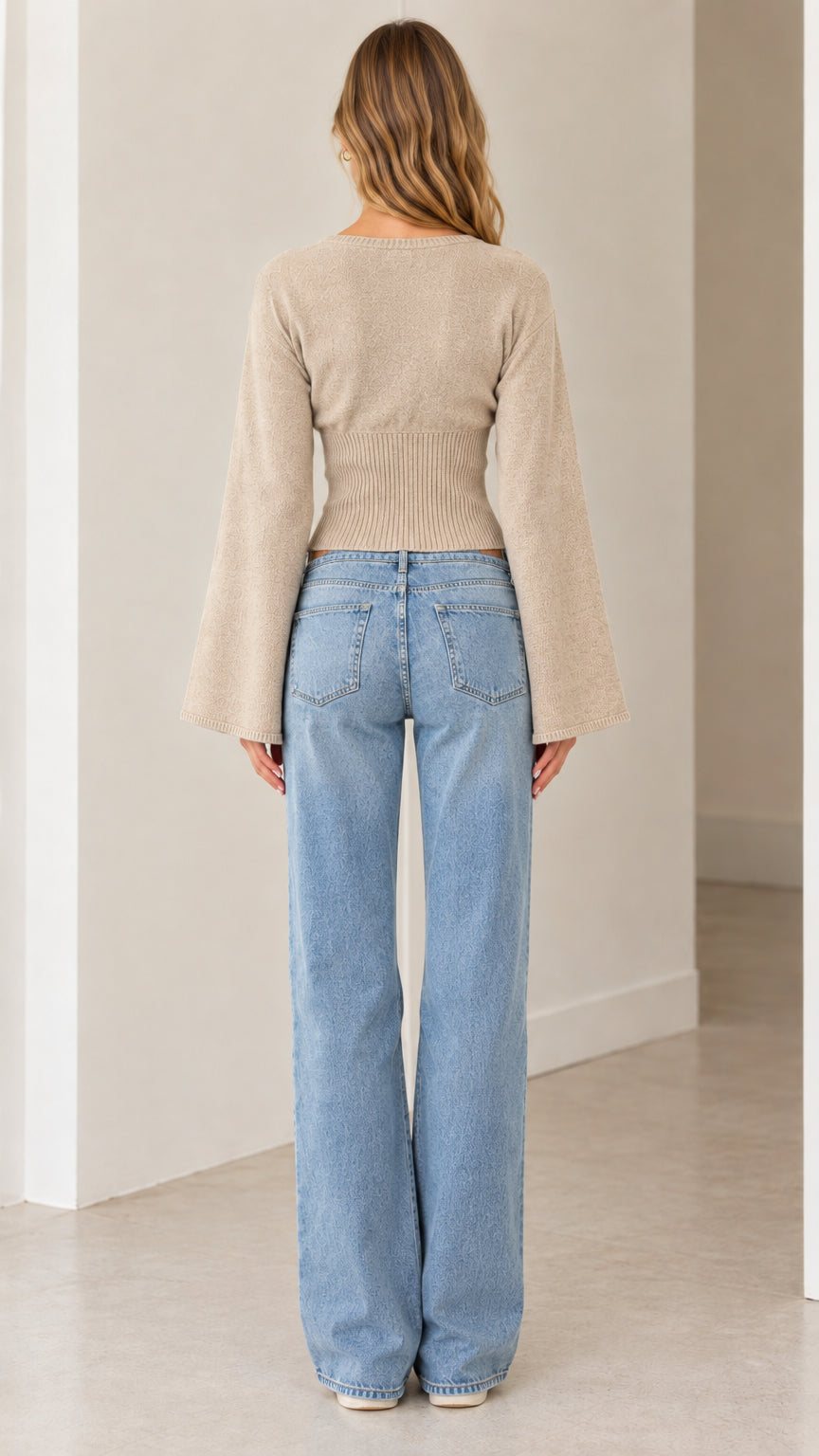 Back view of model wearing beige flared sleeve knit cardigan with ribbed waist
