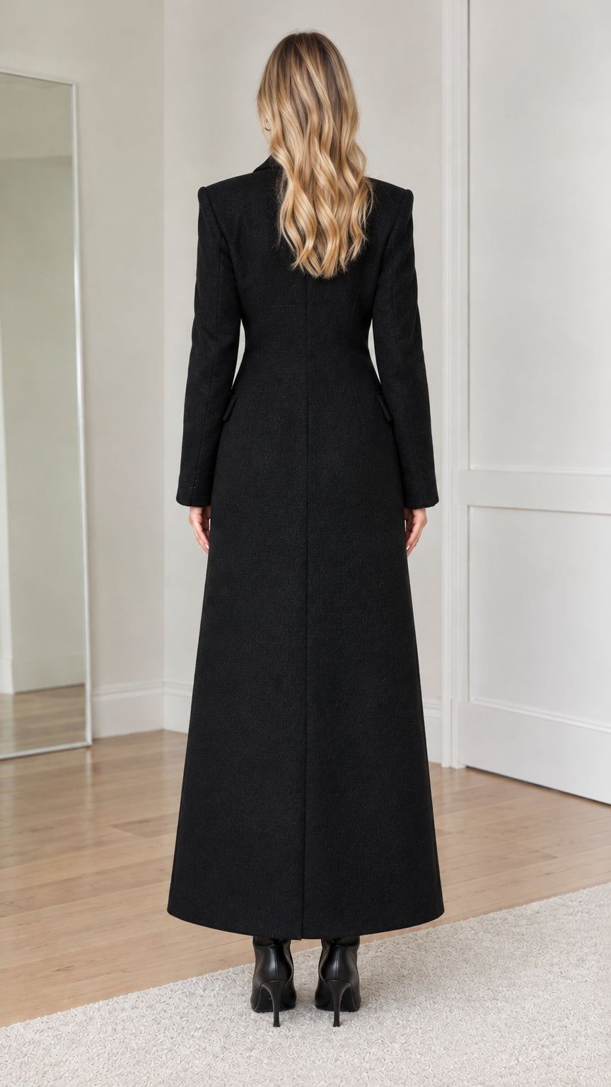 Back view of woman wearing black maxi overcoat with tailored seams