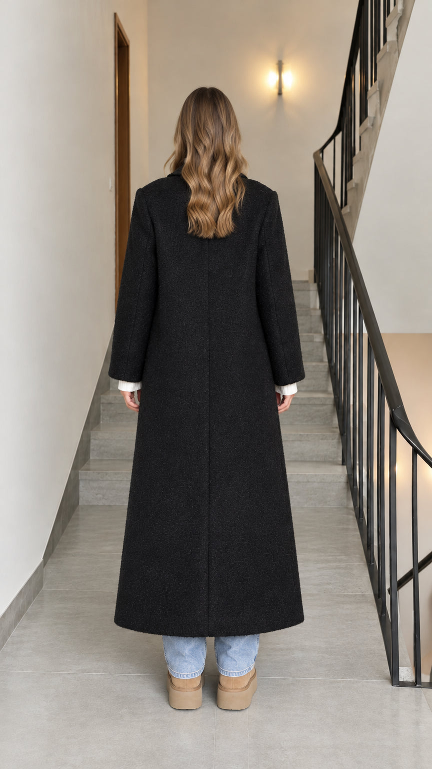 Back view of woman wearing a black longline tailored maxi coat