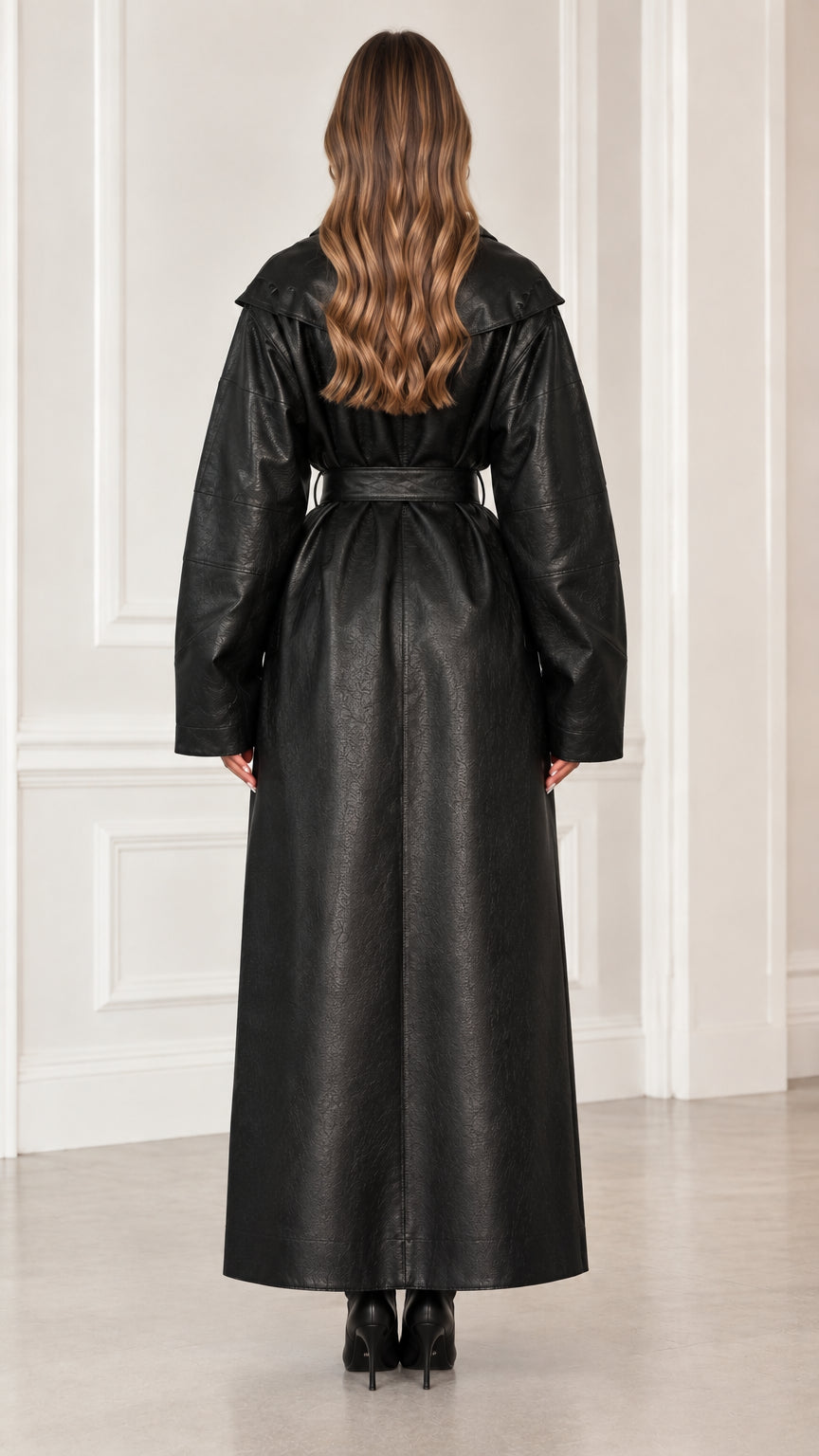 Back view of model wearing long black faux leather trench coat