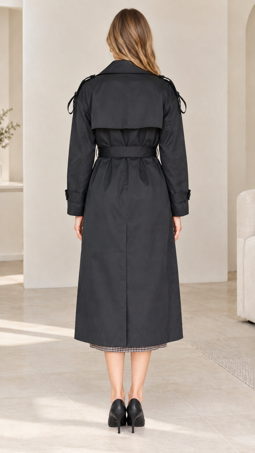 Back view of model wearing black long trench coat showing back storm flap and vent