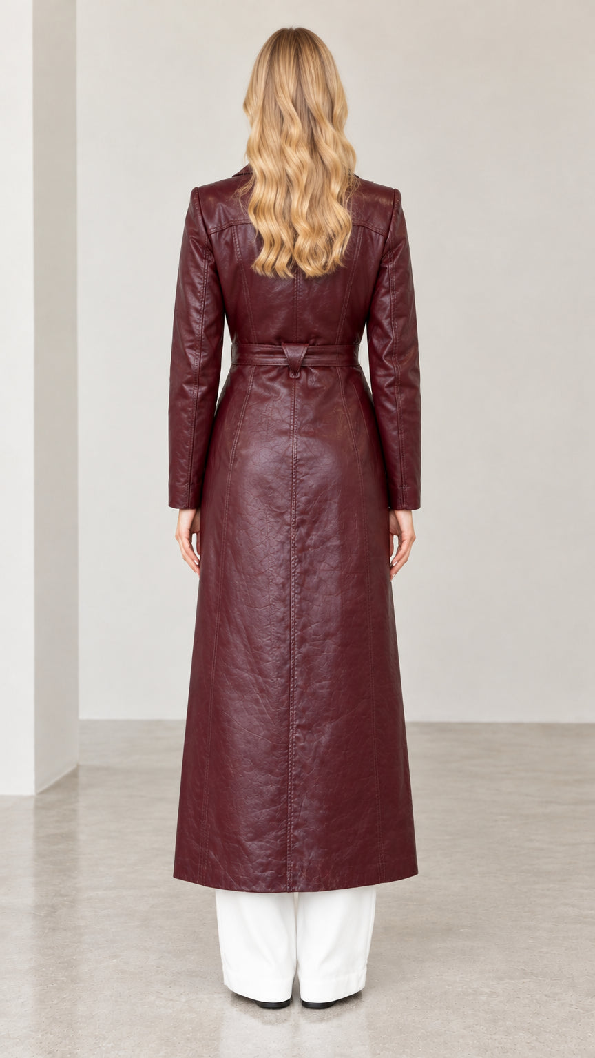 Back view of woman wearing tailored burgundy faux leather duster coat with back waist detail