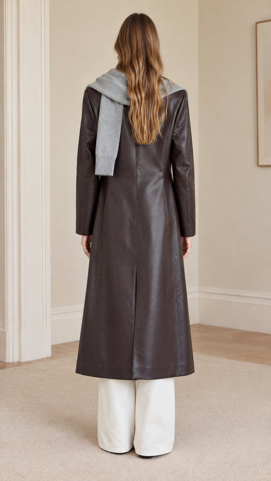 Back view of model wearing dark brown faux leather long trench coat highlighting back vent slit