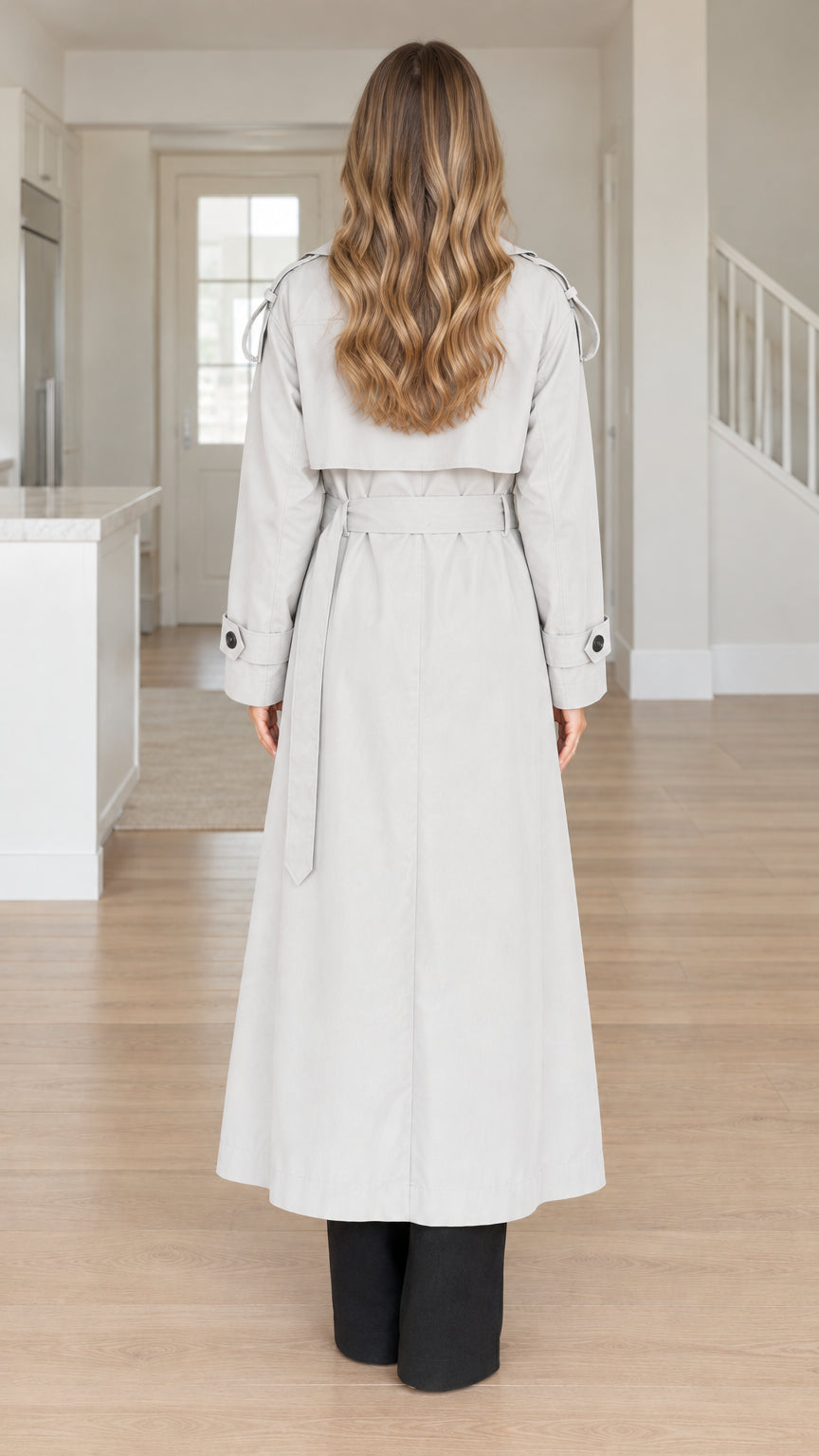Back view of model showing the storm flap and belt on the light grey long trench coat