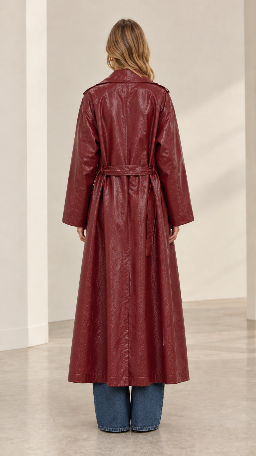Back view of burgundy long trench coat showing tied belt and center vent