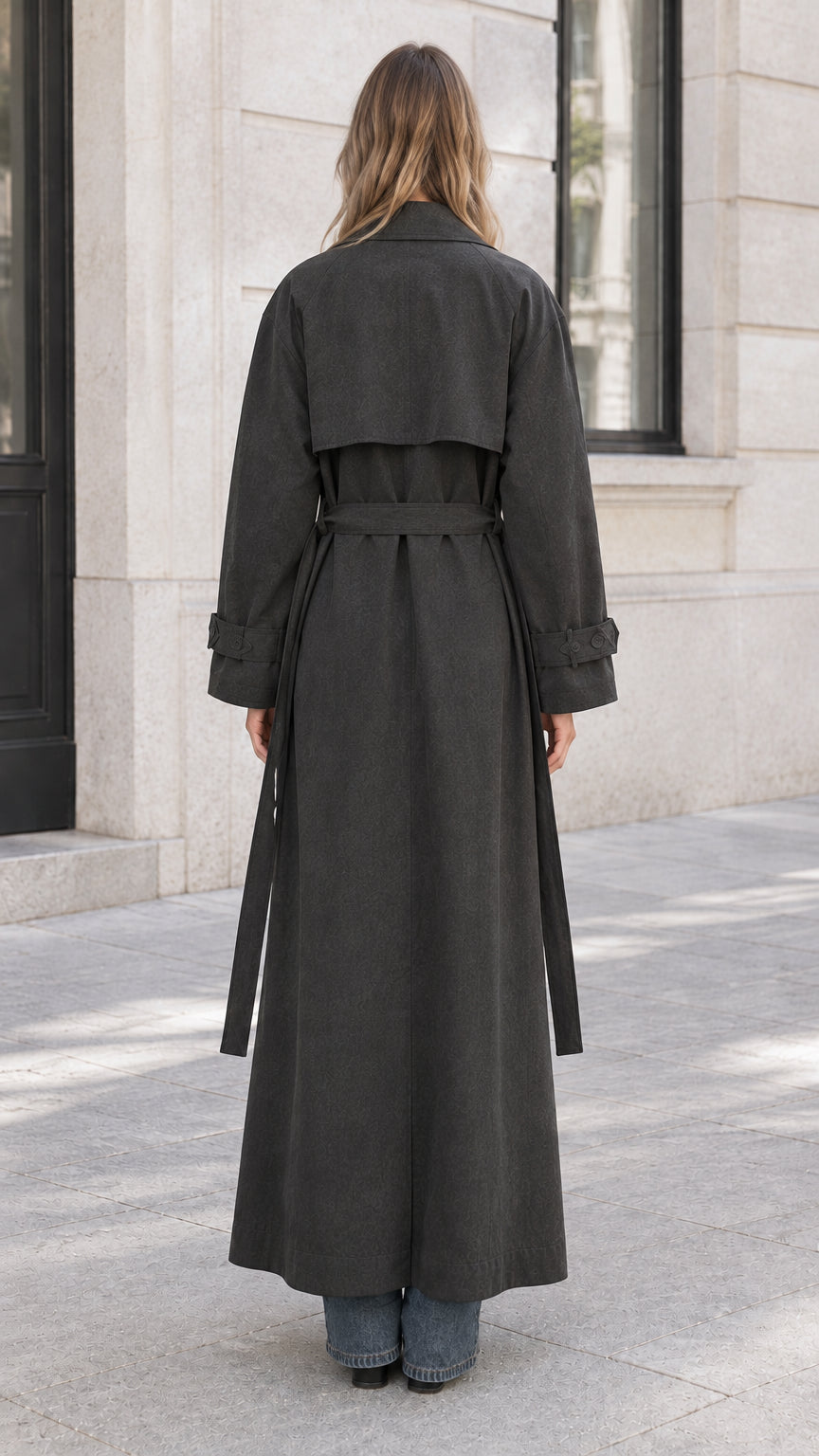 Back view of woman showing the full-length charcoal maxi coat and storm flap detail