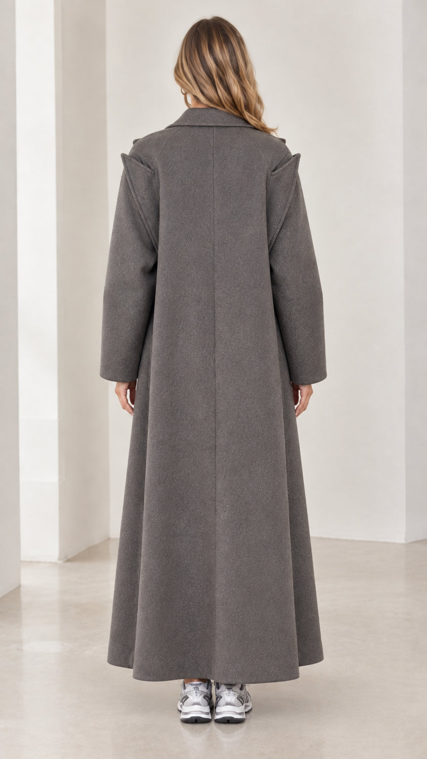 Rear view of model showcasing longline drape of charcoal grey overcoat