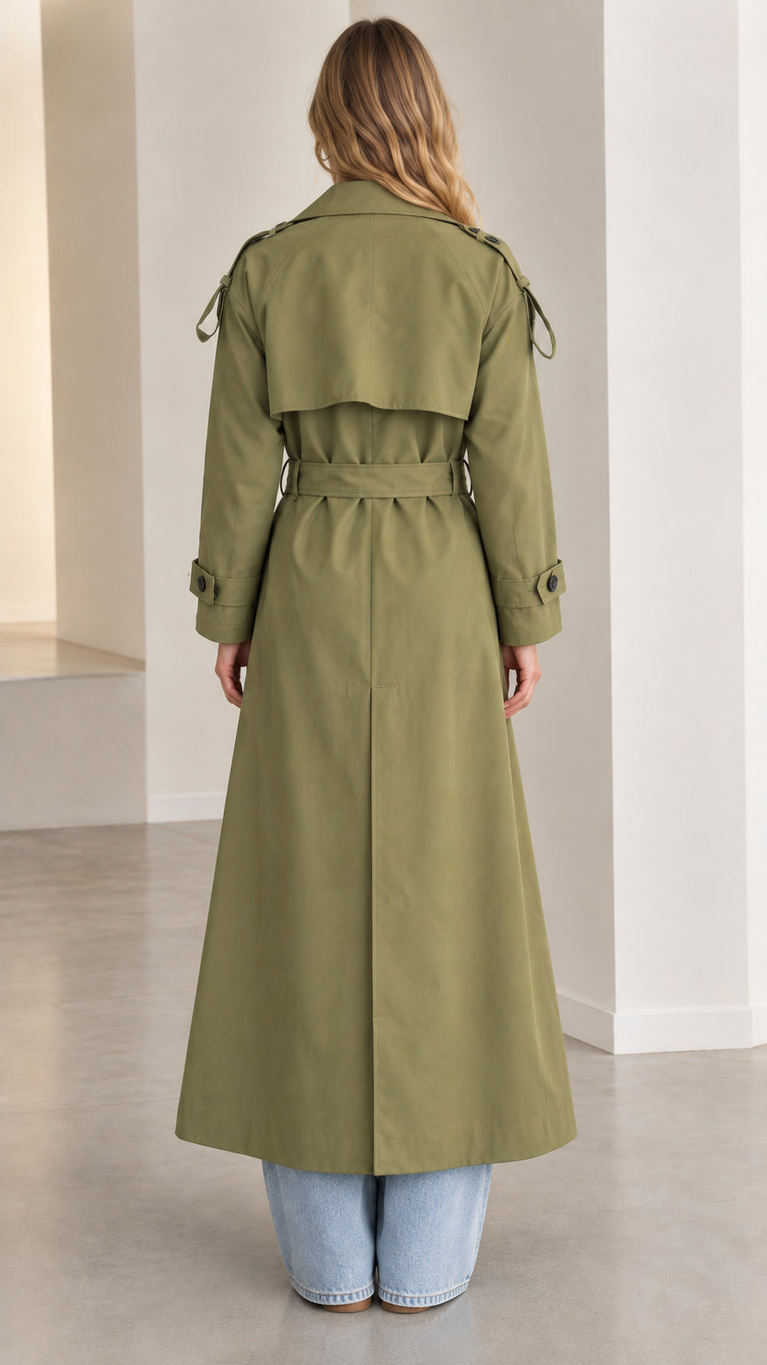 Back view of woman wearing the olive green maxi trench coat showing back storm flap and belt
