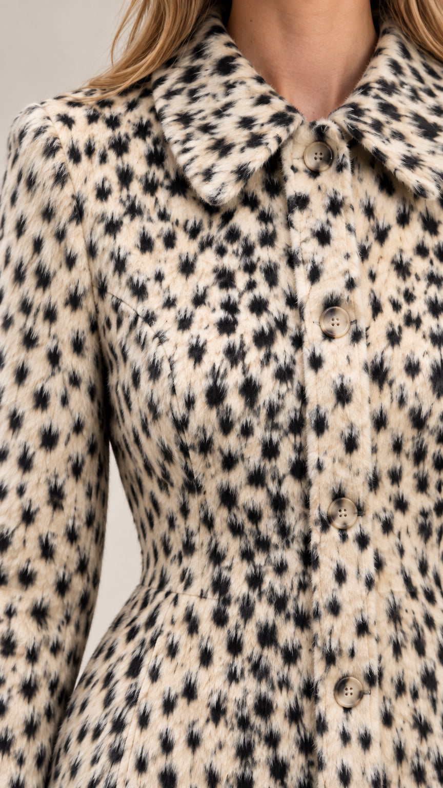 Close-up detail of textured fabric, spread collar, and front buttons on cream animal print jacket