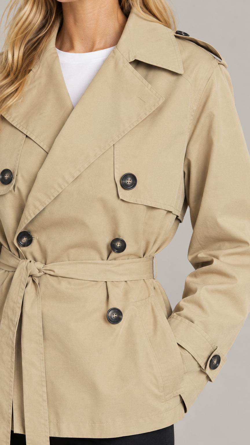 Close-up detail of khaki short trench coat featuring lapels, buttons, and waist tie