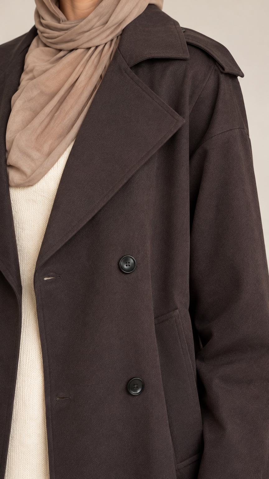 Close-up detail of dark brown trench coat collar, notched lapels, and buttons