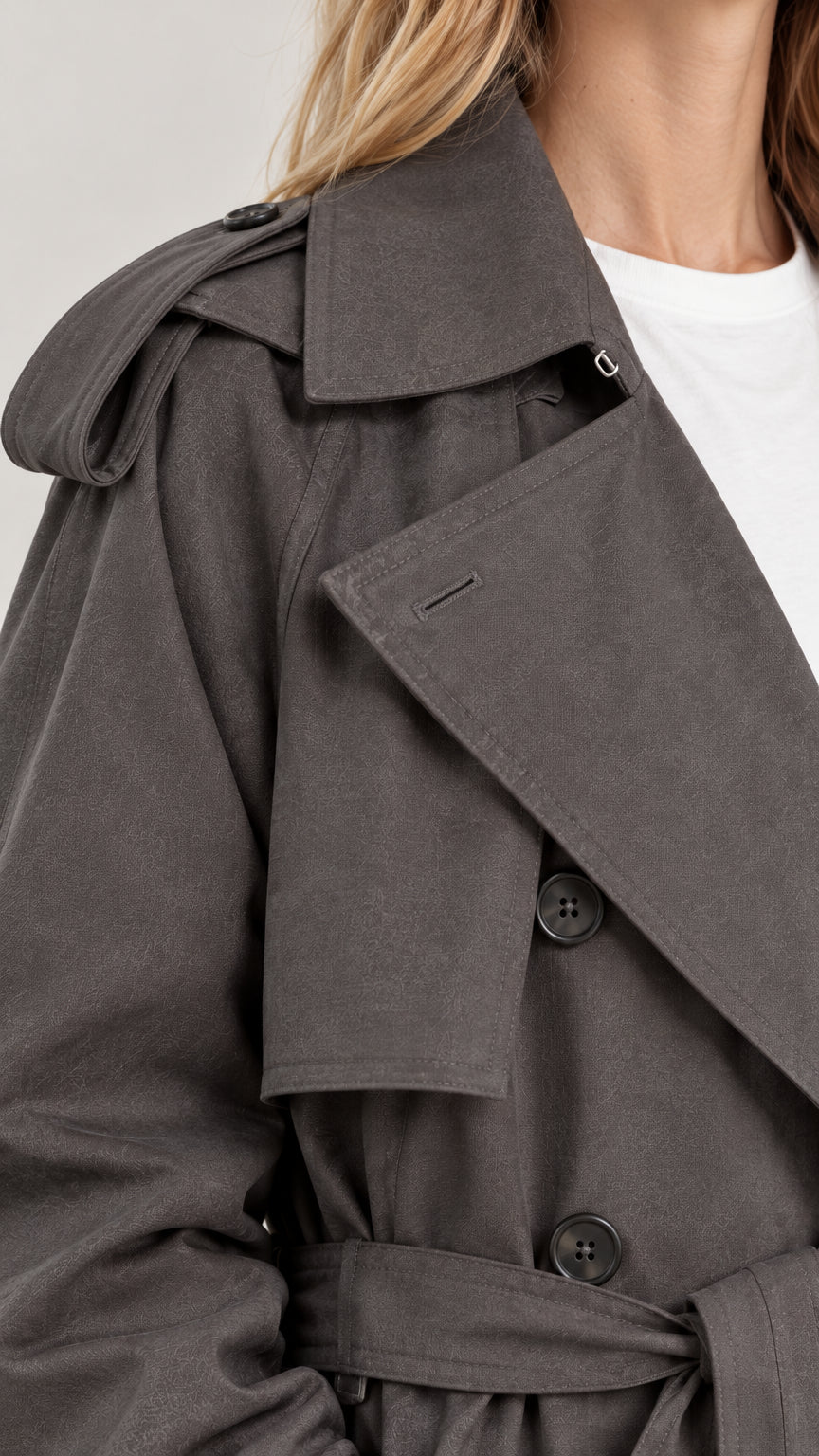 Close-up detail of charcoal grey trench coat showing wide lapels, buttons, and shoulder epaulettes