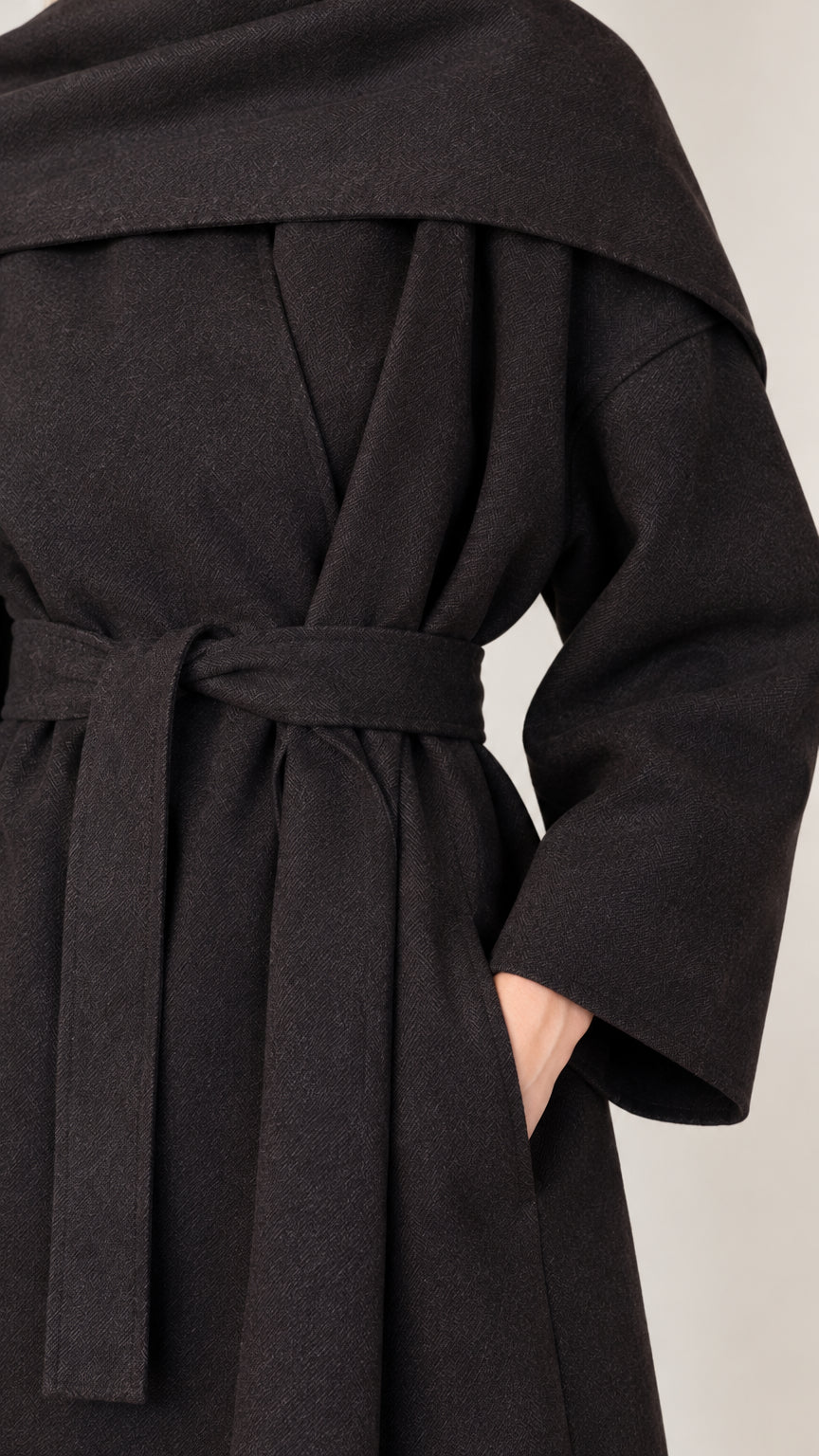 Close-up detail of textured black fabric, side pocket, and tied fabric belt