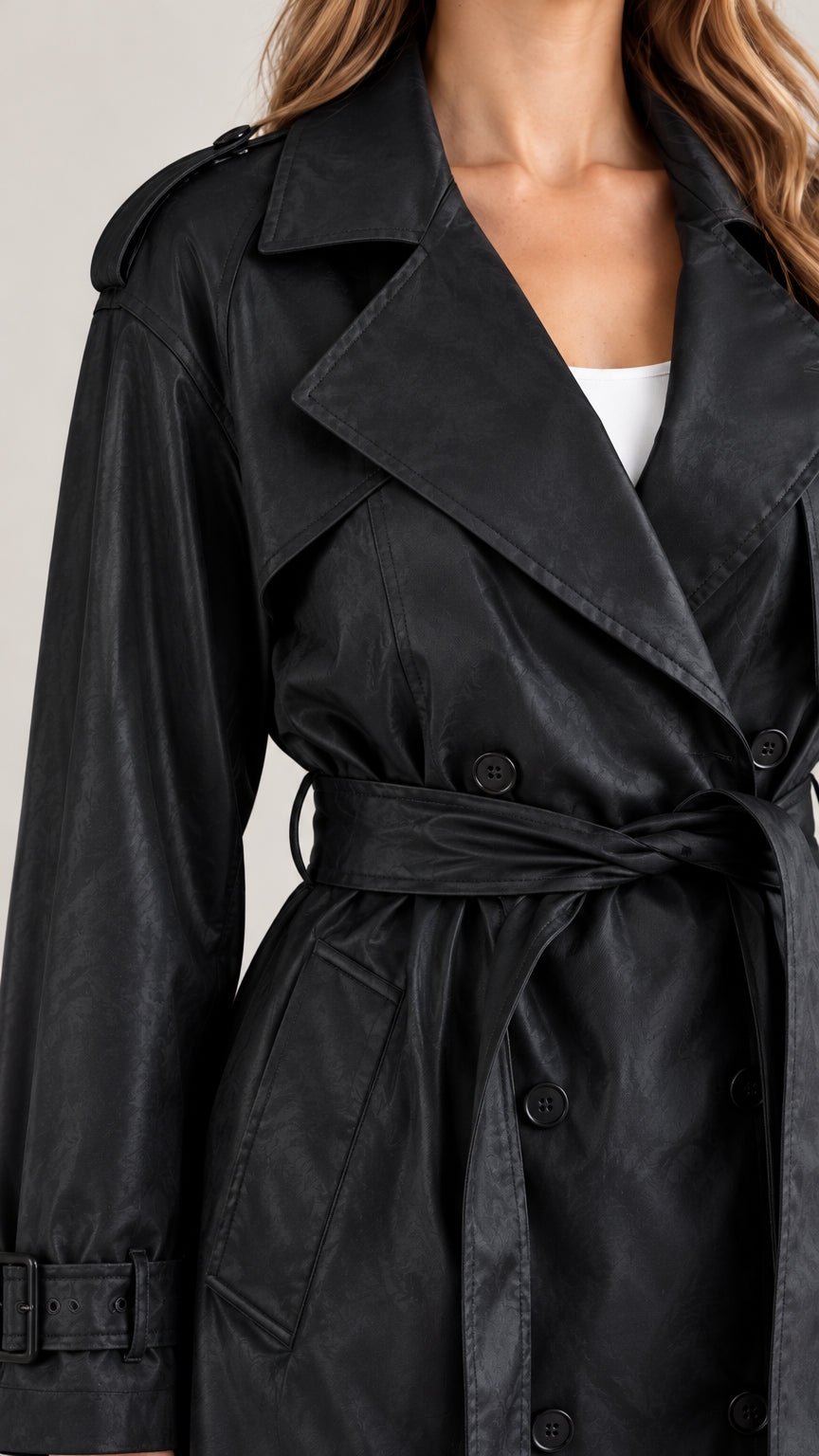 Close-up detail of the black trench coat collar, double-breasted buttons, and wrist straps