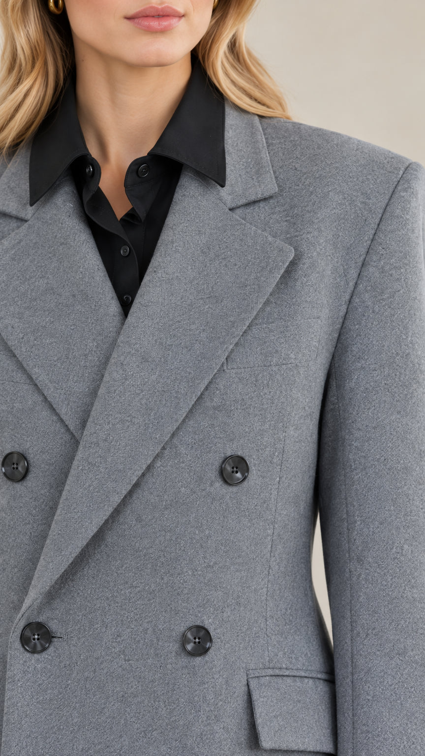 Close-up detail of peak lapels and double-breasted buttons on grey tailored coat