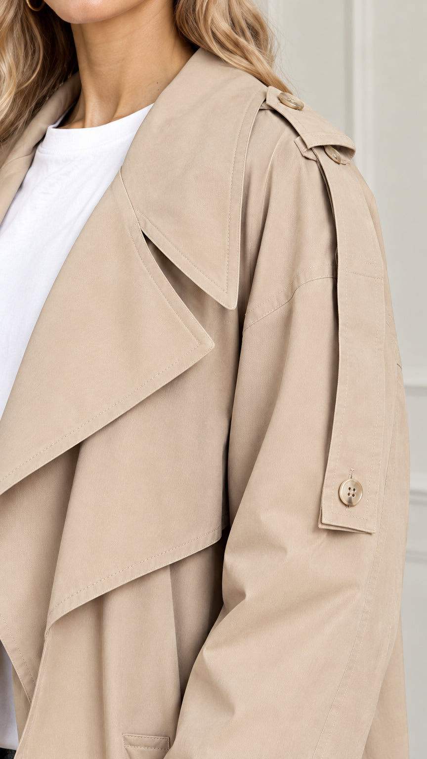 Close-up detail of beige trench coat wide drape lapels and shoulder epaulette button