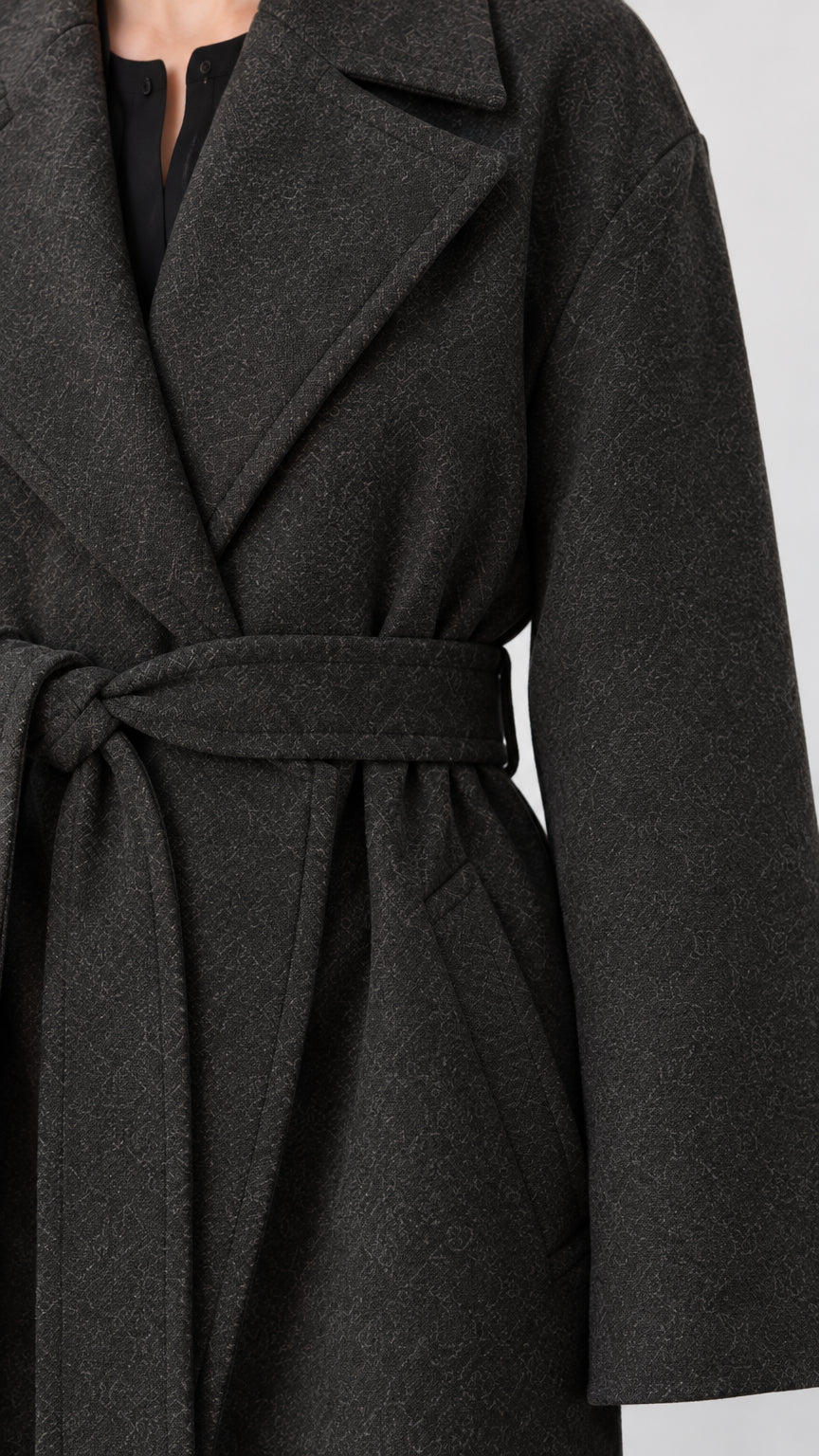 Close-up detail of dark grey coat textured fabric, notched lapel, and tied belt