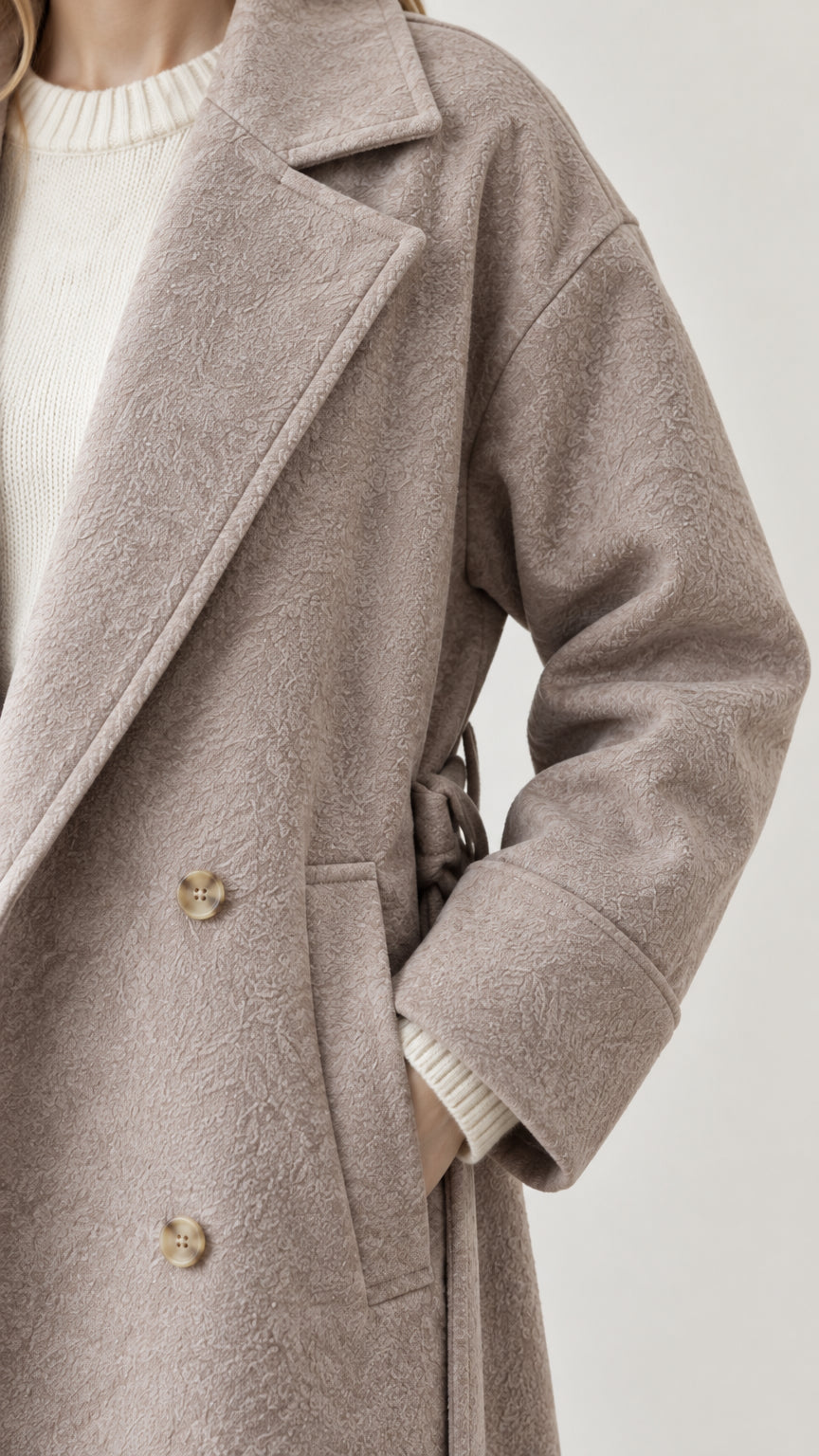 Close-up detail of textured fabric, wide notched lapel, and button accents on taupe coat