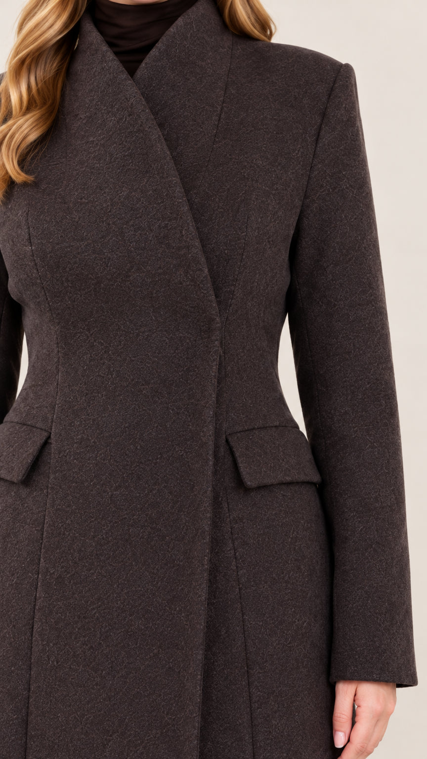 Close-up detail of high crossover collar and flap pockets on charcoal coat