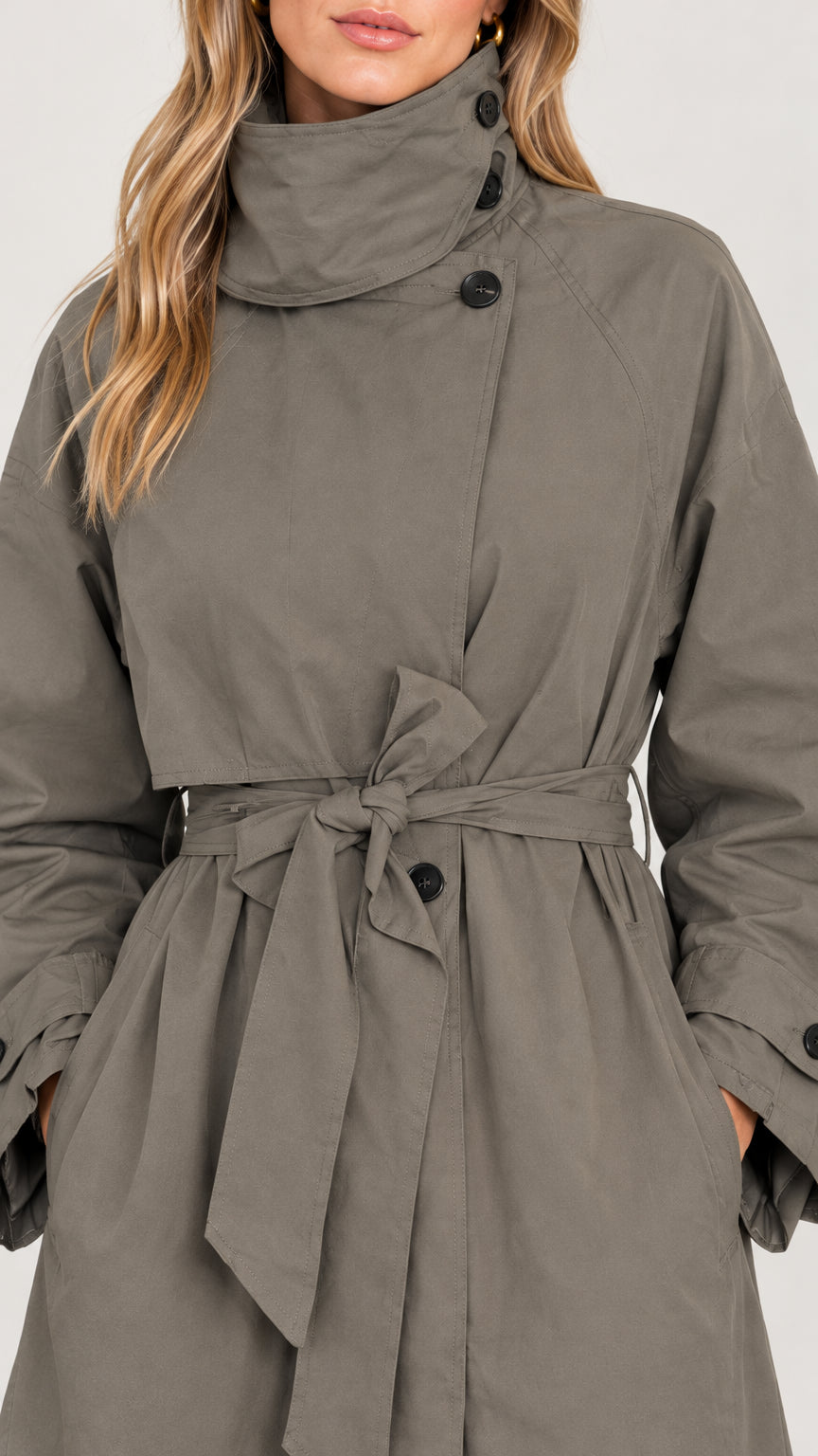 Close-up detail of high buttoned funnel collar and belted waist on olive green trench coat