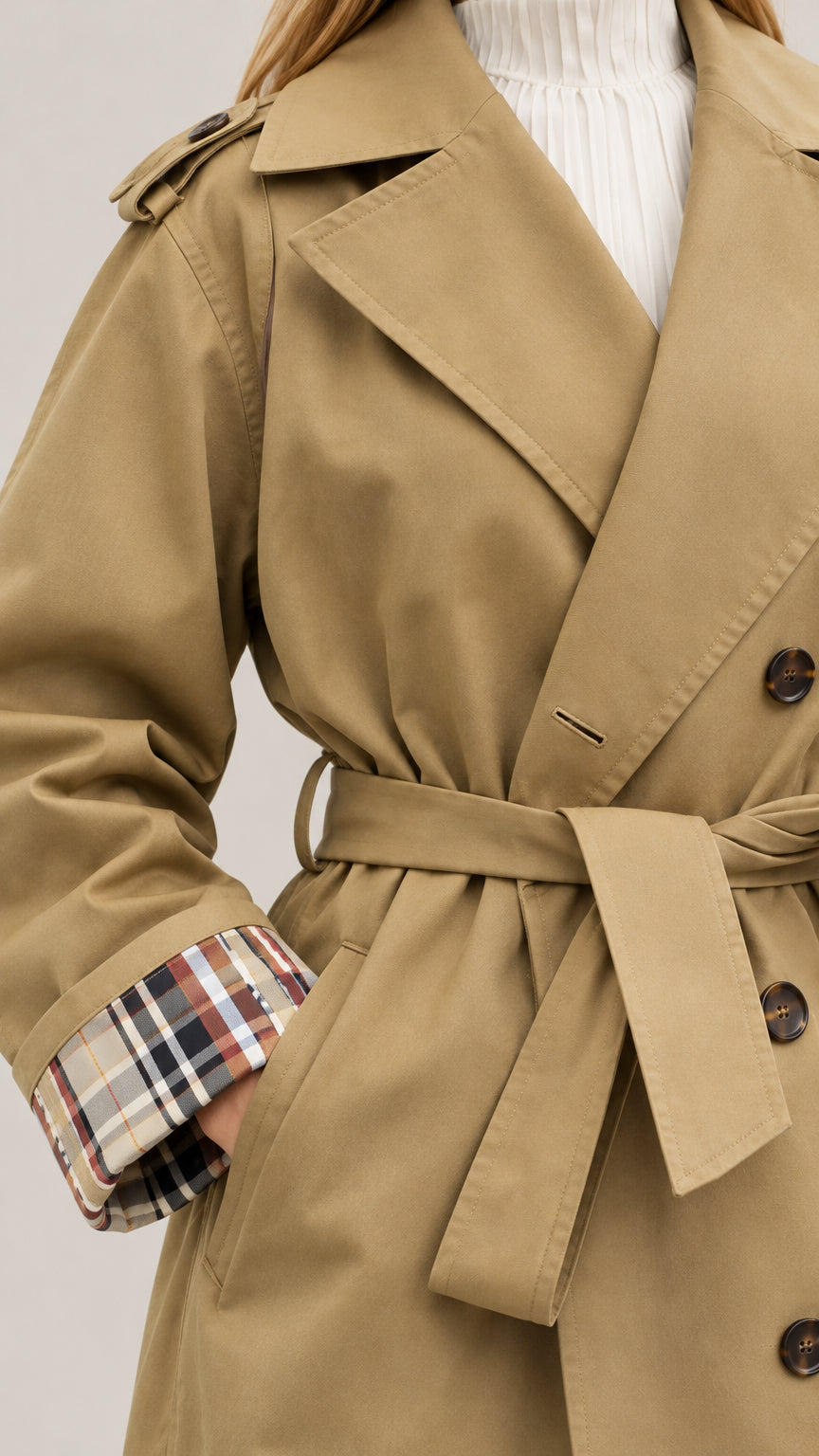 Close-up detail of lapel, double-breasted buttons, and plaid fold-over cuff on camel coat