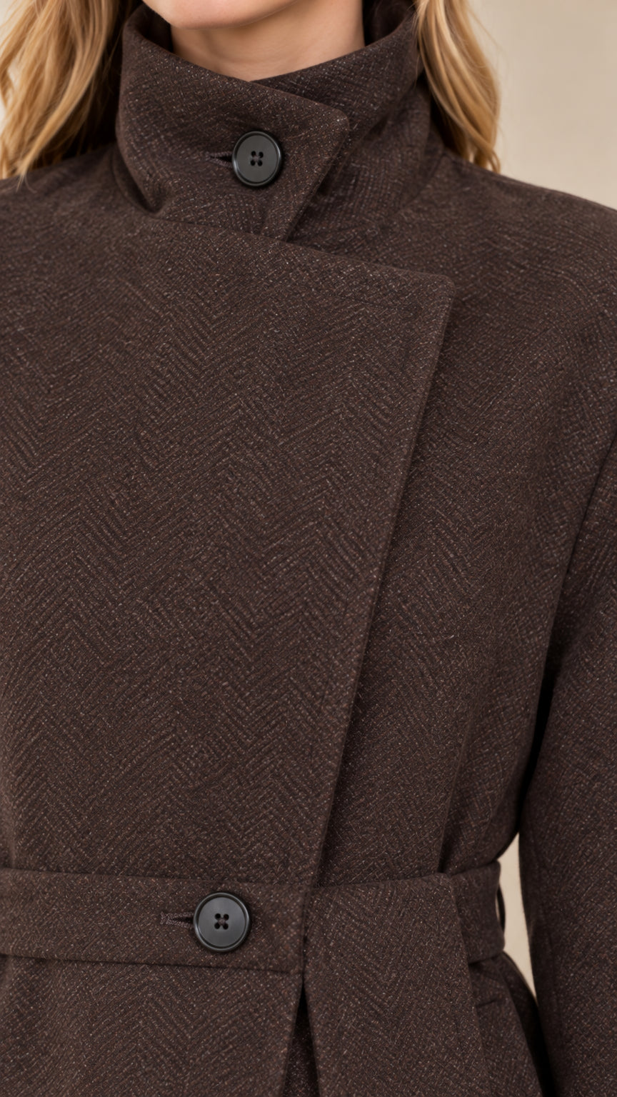 Close-up detail of textured woven herringbone fabric, high asymmetric button collar, and waist belt
