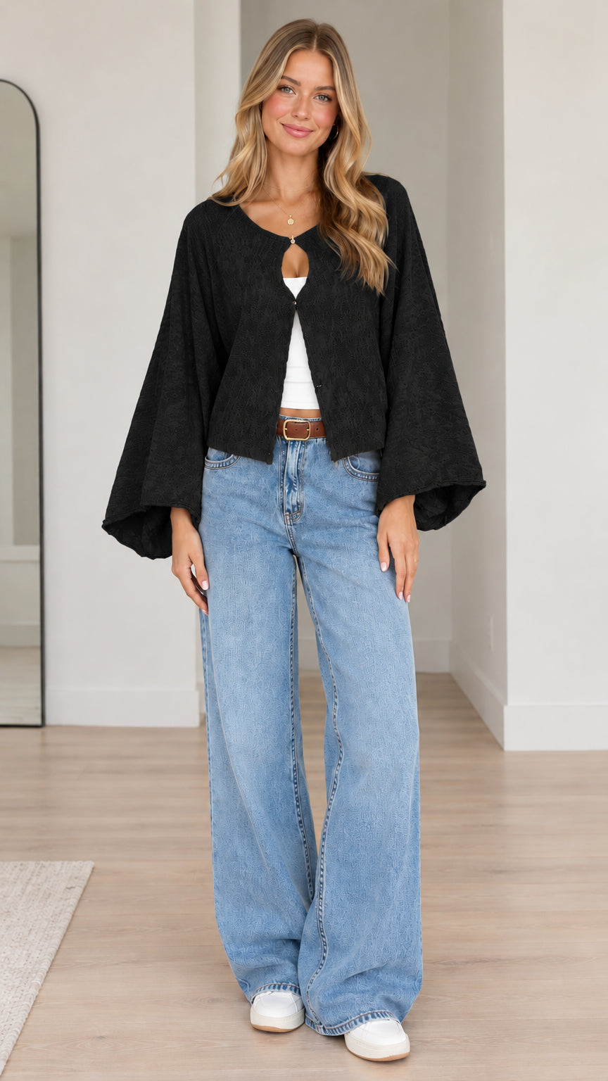 Model wearing black textured bell sleeve cardigan with wide leg denim