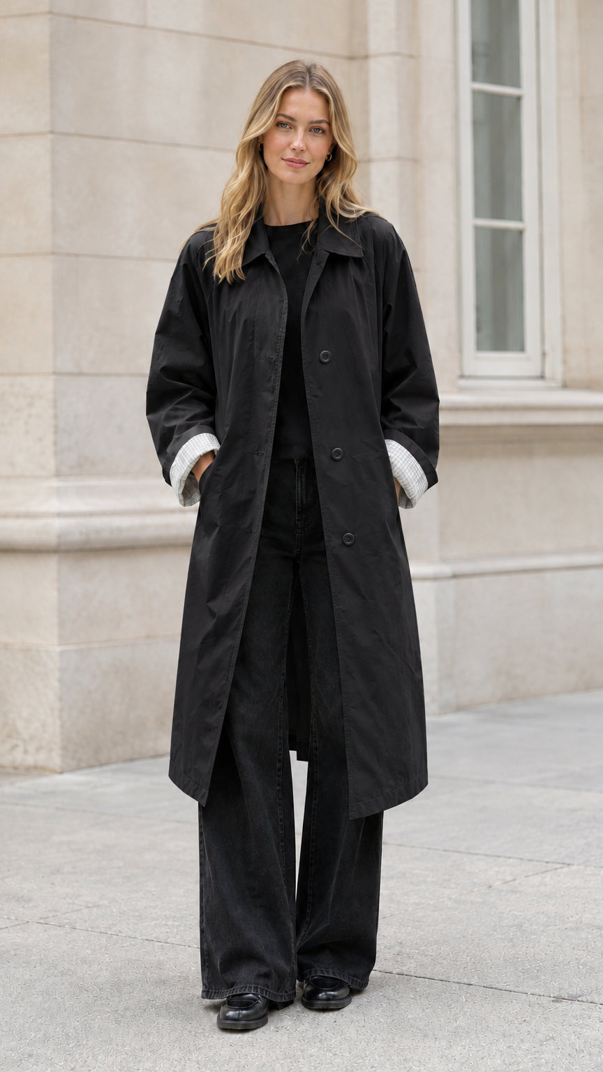 Front full-length view of model wearing a black long belted trench coat