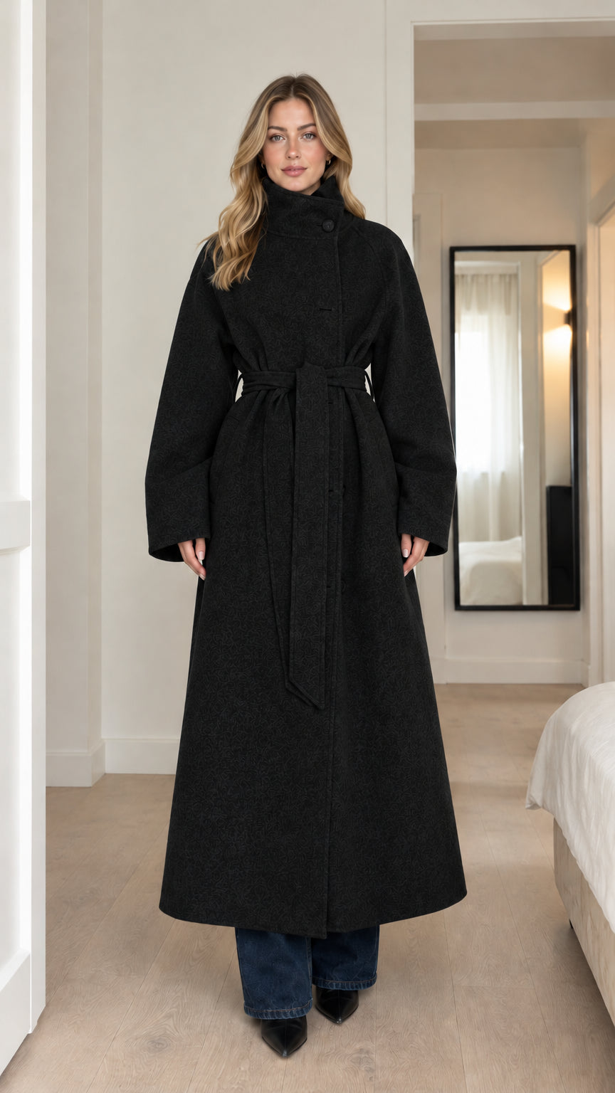 Front full-length view of model wearing black high-neck belted maxi coat